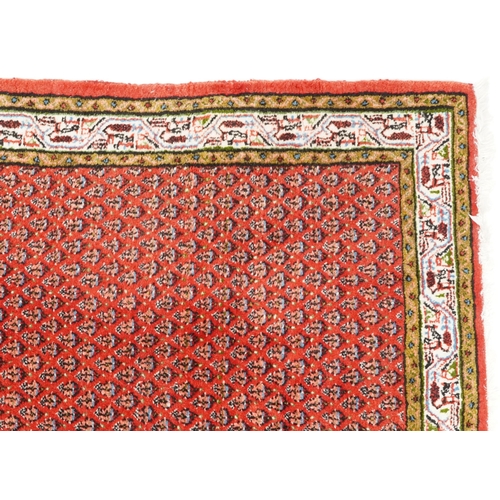 1094 - A Hamadan rug, late 20th century, the red field with an allover flower head design within a compleme... 