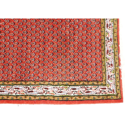 1094 - A Hamadan rug, late 20th century, the red field with an allover flower head design within a compleme... 