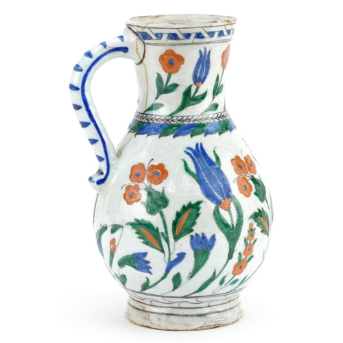 194 - A Turkish Ottoman Iznik pottery water jug hand painted with flowers, 24cm high.