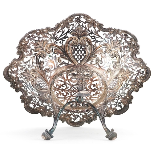 389 - An Edwardian silver centrepiece bowl, raised on three feet, profusely embossed and pierced with flow... 