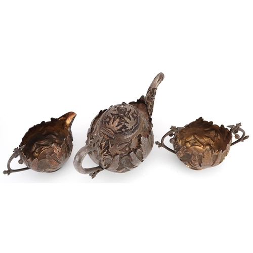 437 - A Middle Eastern white metal naturalistic three piece tea set profusely embossed with foliage and fr... 