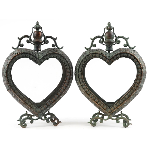 1565 - A pair of ornate bronzed metal love heart candleholders with glass panels, each 53cm high.