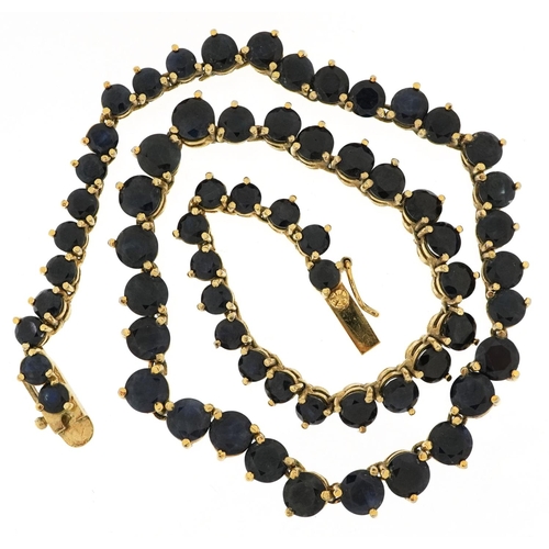 3039 - A vintage gold plated sapphire necklace set with sixty four solitaire sapphires, the largest sapphir... 