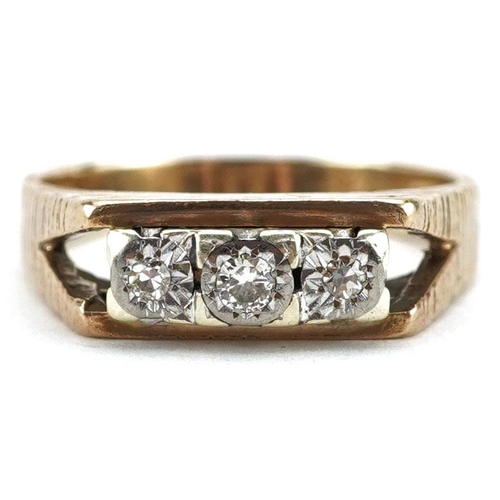 3072 - A 9ct gold diamond three stone ring with engine turned shoulders, size O, 4.4g.