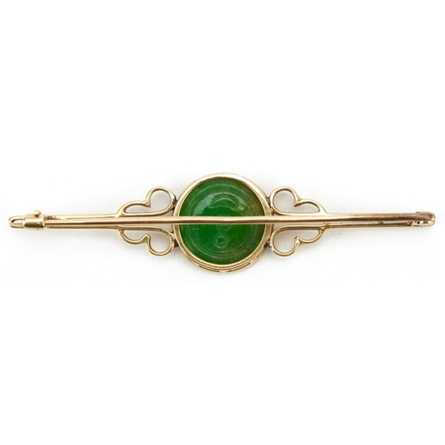 3019 - A Chinese unmarked gold bar brooch set with a carved green jade panel, 6cm wide, 5.2g.