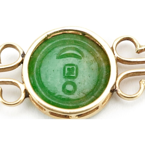 3019 - A Chinese unmarked gold bar brooch set with a carved green jade panel, 6cm wide, 5.2g.