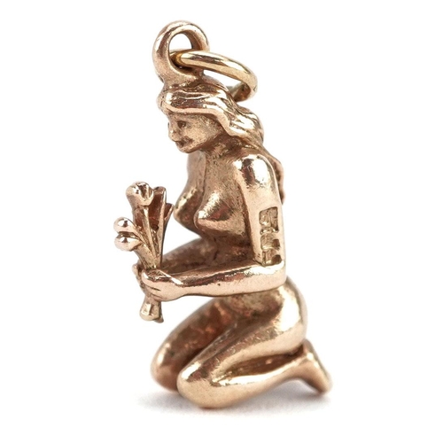 A 9ct gold charm in the form of a kneeling nude female holding flowers, 2cm high, 3.0g.