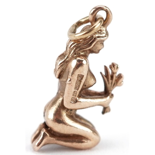  A 9ct gold charm in the form of a kneeling nude female holding flowers, 2cm high, 3.0g.