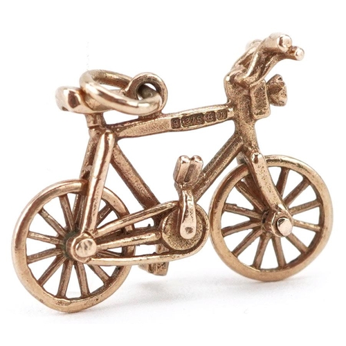  A 9ct gold charm in the form of a bicycle with rotating wheels, 2.1cm in length, 1.8g.