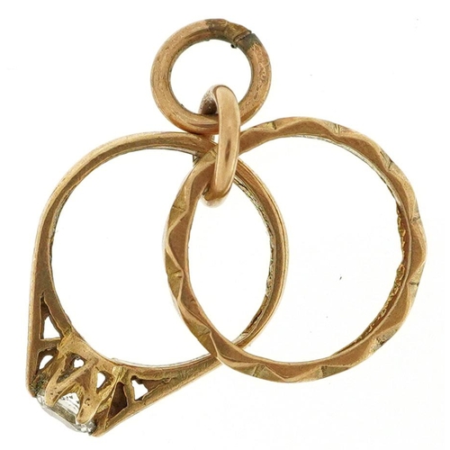 600 - A 9ct gold charm in the form of an engagement ring and wedding ring, 1.6cm high, 1.6g.