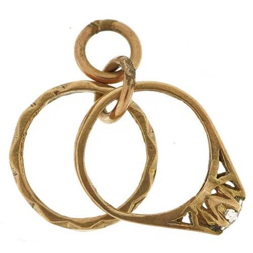 600 - A 9ct gold charm in the form of an engagement ring and wedding ring, 1.6cm high, 1.6g.