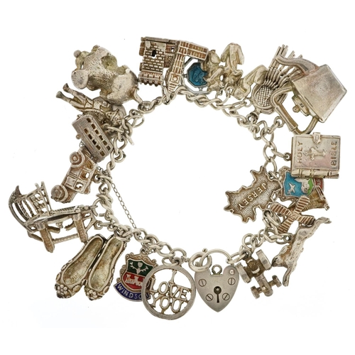 438 - A silver charm bracelet with a collection of mostly silver charms including Nelson, tractor and wind... 