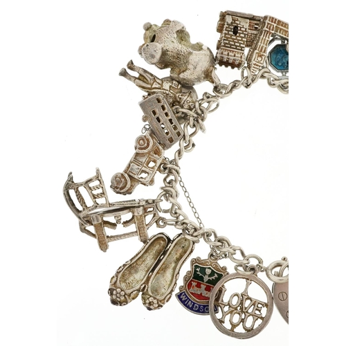 438 - A silver charm bracelet with a collection of mostly silver charms including Nelson, tractor and wind... 