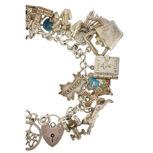 438 - A silver charm bracelet with a collection of mostly silver charms including Nelson, tractor and wind... 