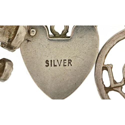 438 - A silver charm bracelet with a collection of mostly silver charms including Nelson, tractor and wind... 