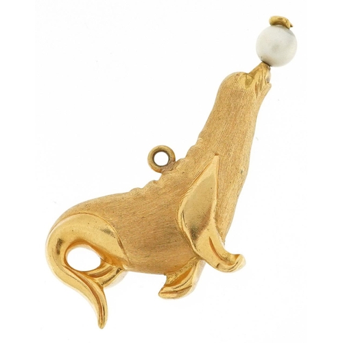 321 - A large unmarked gold charm in the form of a seal balancing a pearl ball, (tests as 9ct gold), 2.3cm... 