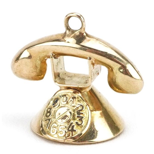 386 - An unmarked gold charm in the form of a vintage dial telephone, 1.3cm high, 1.0g.