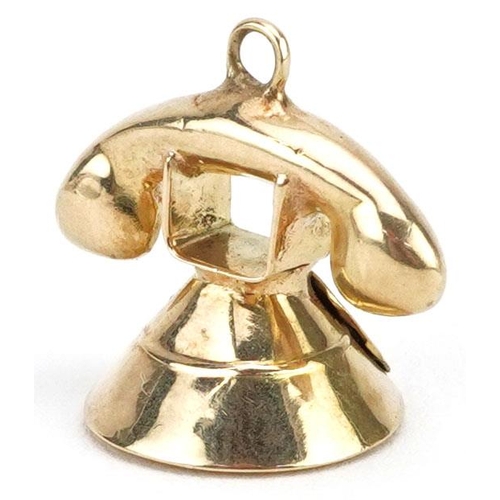 386 - An unmarked gold charm in the form of a vintage dial telephone, 1.3cm high, 1.0g.