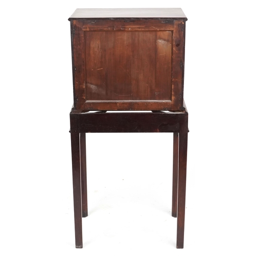 1002 - A George III figured mahogany collector's cabinet on stand, the panelled doors revealing eight drawe... 