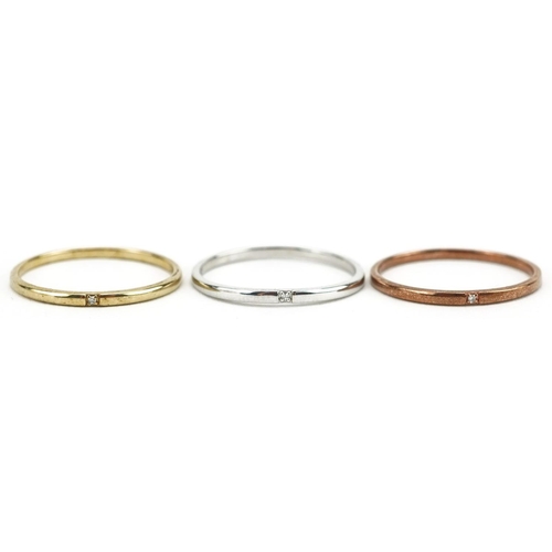 587 - A set of three 9ct three tone gold wedding bands, each set with a solitaire diamond, size M/N, total... 