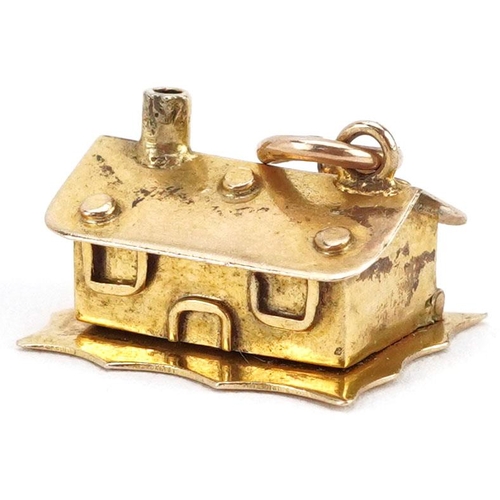 231 - A 9ct gold charm in the form of a cottage opening to reveal figures in a bed, 1.5cm wide, 2.4g.