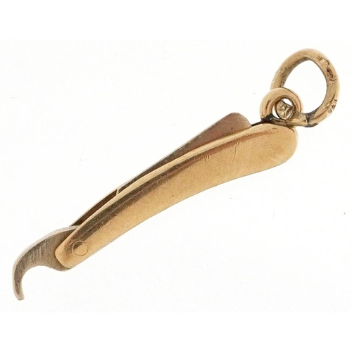 589 - A 9ct gold charm in the form cut throat razor, 2cm in length, 0.8g.