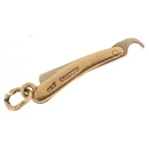 589 - A 9ct gold charm in the form cut throat razor, 2cm in length, 0.8g.