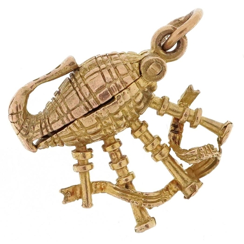 403 - A 9ct gold charm in the form bagpipes opening to reveal an enamel Scotsman, 1.7cm high, 3.1g.