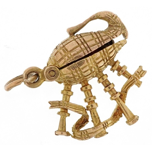 403 - A 9ct gold charm in the form bagpipes opening to reveal an enamel Scotsman, 1.7cm high, 3.1g.