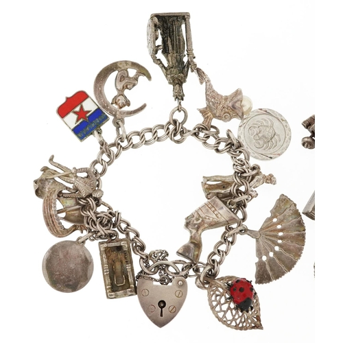 384 - Two silver charm bracelets with a collection of mostly silver charms including a matador, Nefertiti ... 