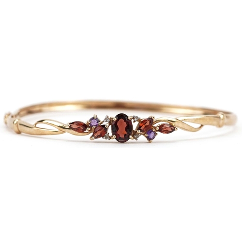 414 - A 9ct gold multi gem hinged bangle set with garnets, diamonds and amethyst, 6cm in diameter, 4.0g.