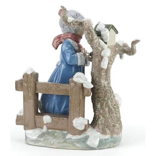 724 - A Lladro figure of a child holding a bird beside a tree - Winter Girl, numbered 5287, 26cm high, wit... 