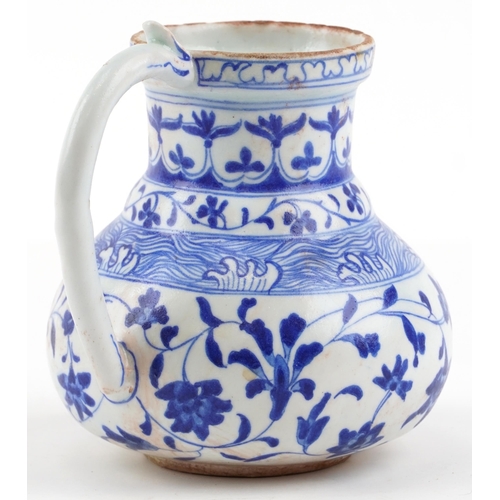 169 - A Turkish Ottoman Iznik jug hand painted with stylized flowers and motifs, 17cm high.