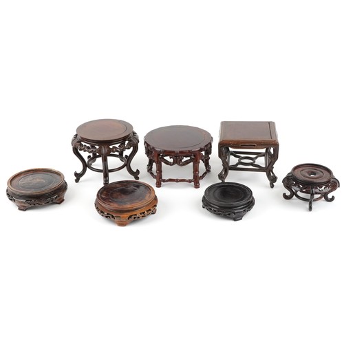 Seven Chinese carved hardwood stands, the largest 15cm high x 18cm in diameter.