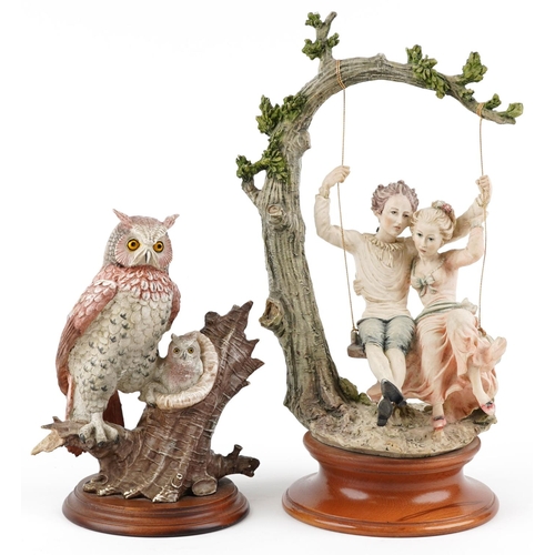 1297 - A Giuseppe Armani Capodimonte 'Lovers on a swing' porcelain figure group raised on a turned wood pli... 