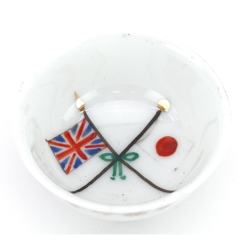 766 - A Japanese military interest hand painted porcelain tea bowl with paper labels, 5cm in diameter.