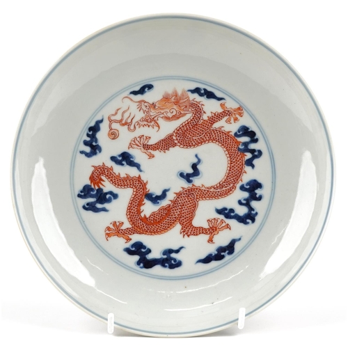 140 - A Chinese porcelain shallow dish hand painted in blue and iron red with a dragon amongst clouds, cha... 