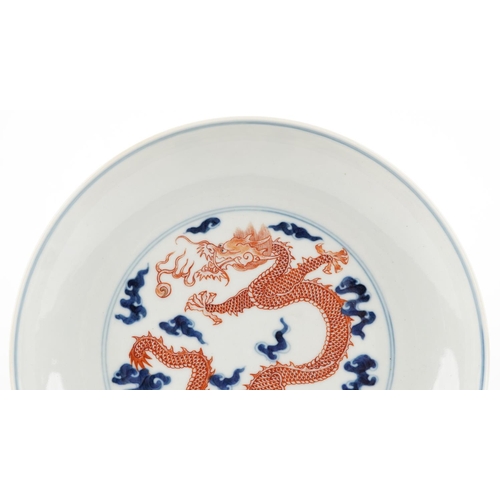 140 - A Chinese porcelain shallow dish hand painted in blue and iron red with a dragon amongst clouds, cha... 