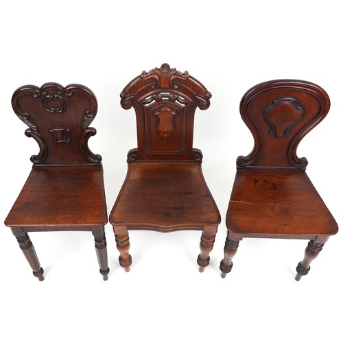 1025 - A group of three Victorian mahogany hall chairs, variously decorated, the largest 88cm high.