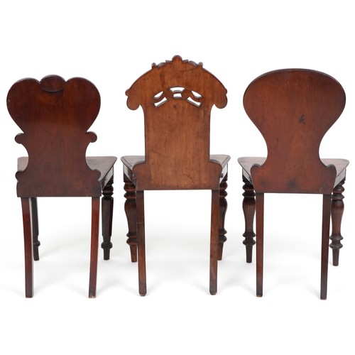 1025 - A group of three Victorian mahogany hall chairs, variously decorated, the largest 88cm high.