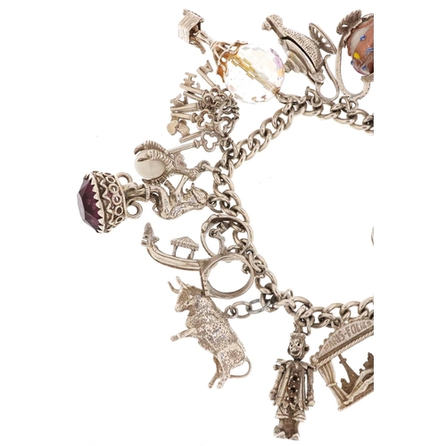 217 - A silver charm bracelet with a large selection of mostly silver charms including Paris Folies Cabare... 