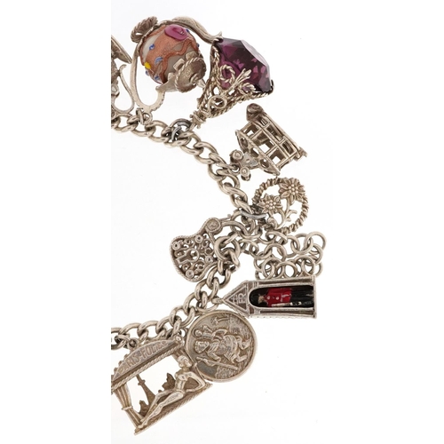 217 - A silver charm bracelet with a large selection of mostly silver charms including Paris Folies Cabare... 