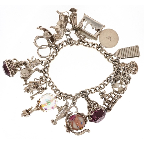 217 - A silver charm bracelet with a large selection of mostly silver charms including Paris Folies Cabare... 