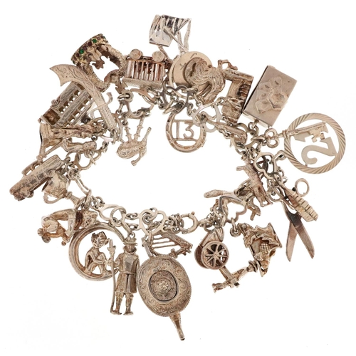 409 - A silver charm bracelet with a large selection of mostly silver charms including a Beefeater, double... 