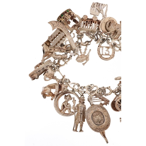 409 - A silver charm bracelet with a large selection of mostly silver charms including a Beefeater, double... 