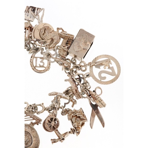 409 - A silver charm bracelet with a large selection of mostly silver charms including a Beefeater, double... 