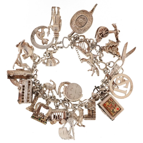 409 - A silver charm bracelet with a large selection of mostly silver charms including a Beefeater, double... 