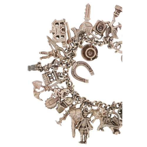 230 - A silver charm bracelet with a large selection of mostly silver charms including a corkscrew, bust o... 