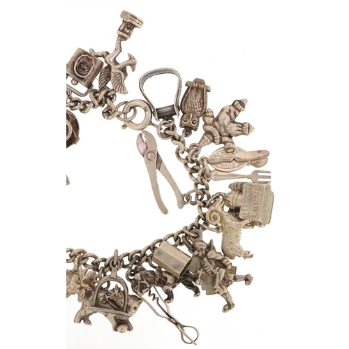 230 - A silver charm bracelet with a large selection of mostly silver charms including a corkscrew, bust o... 