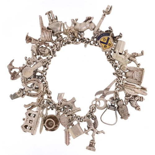 230 - A silver charm bracelet with a large selection of mostly silver charms including a corkscrew, bust o... 